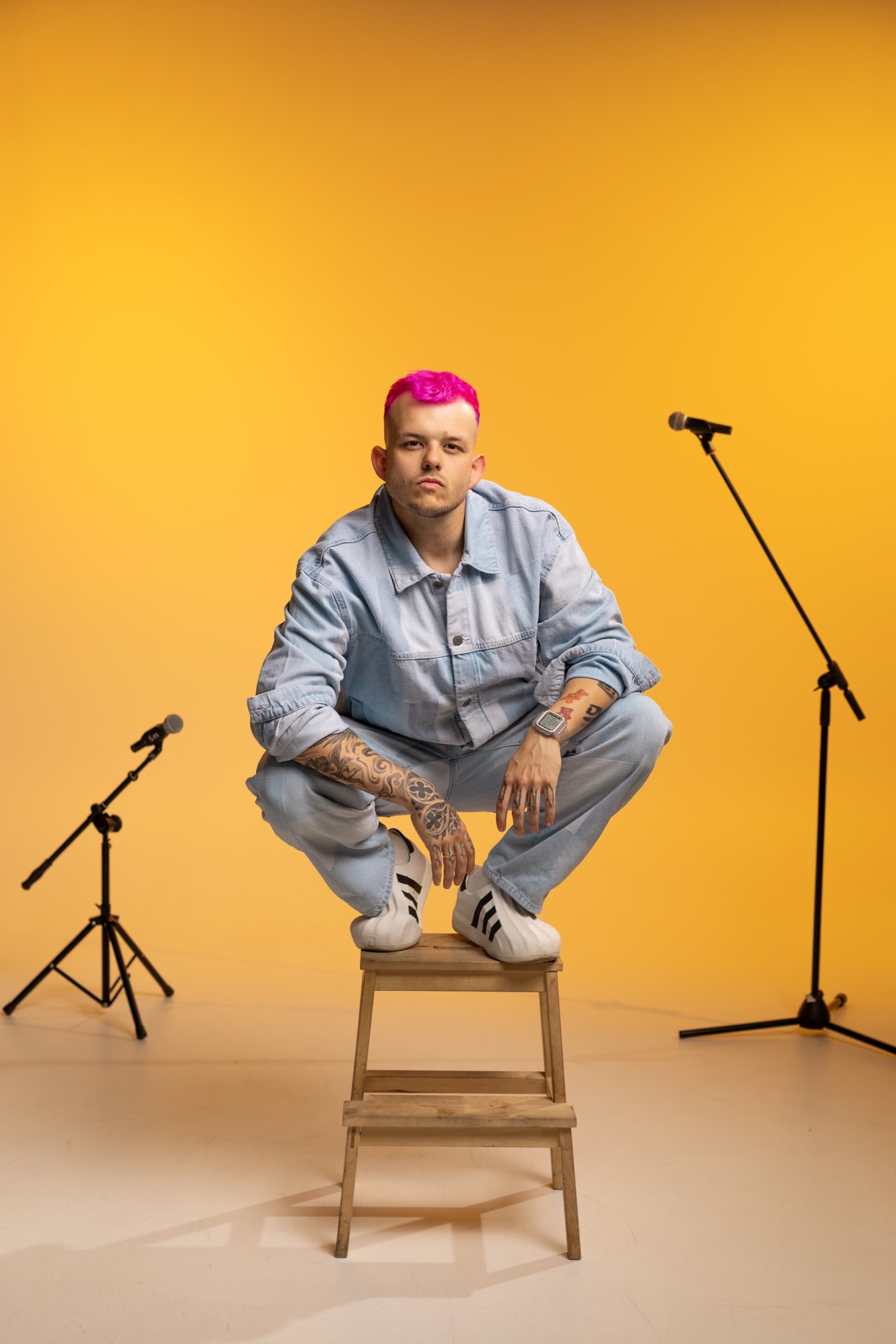 Franek Lakuna na stołku w żółtej scenografii z mikrofonami